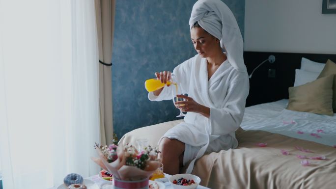 一名女子在酒店房间早餐时倒橙汁