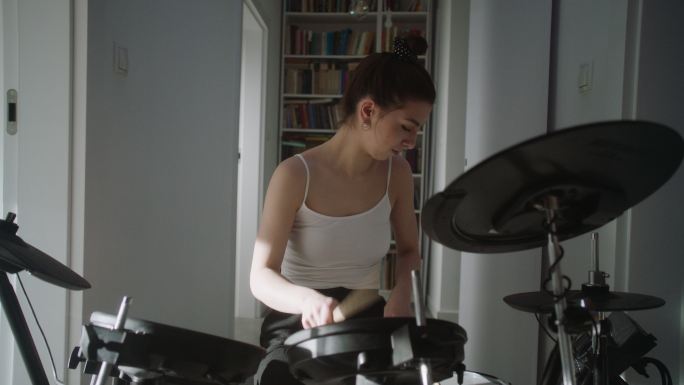 年轻女子在起居室练习电子鼓