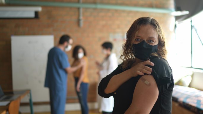 一名中年女性接种疫苗后展示手臂的肖像-使用口罩