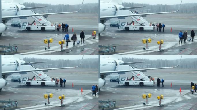 恶劣天气日：乘客从机场航站楼走到飞机登机梯。国际机场登机旅客