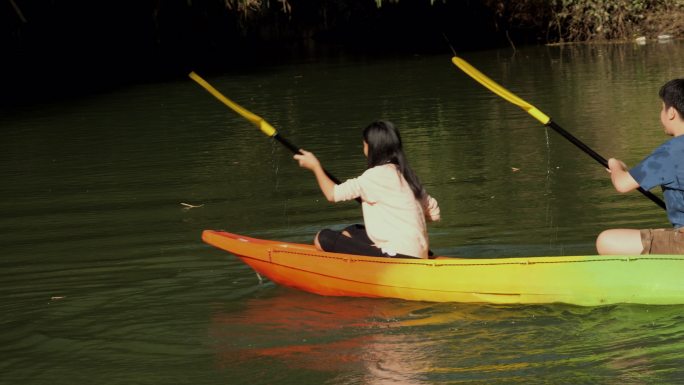 亚洲儿童在湖中学习皮划艇或独木舟，一起享受户外阳光、生活方式的概念。