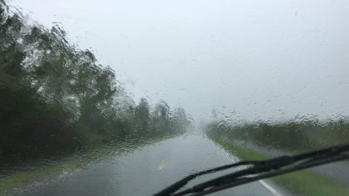 雨刷器无法清除盲雨的乡村森林道路上的驾驶员视野