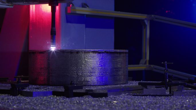 在室内制造设备中，机器人CNC机械臂将一层铝焊接到金属鼓形状上的侧视图