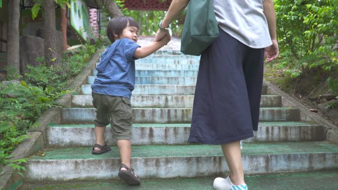亚裔母亲和儿子在公共公园牵手一起上楼