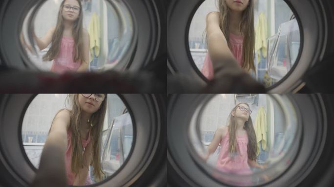 一个戴眼镜、身穿粉色T恤的十几岁女孩从洗衣机里取出干净的衣服。