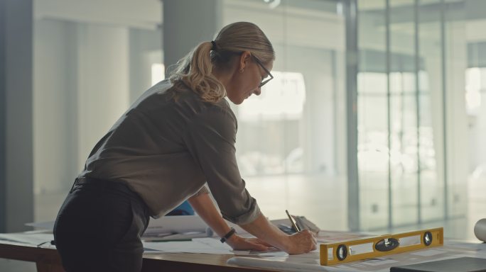 在建筑项目中设计蓝图的女建筑师或工程师。一个女人在画建筑平面图