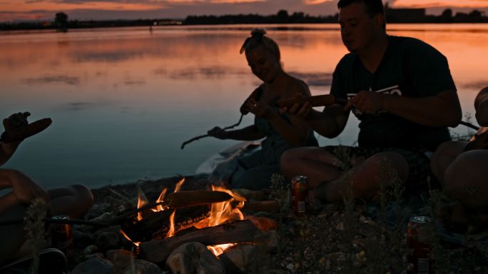 SLO MO黄昏时一群年轻人在湖边露营