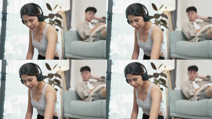年轻的亚洲女性正在准备健身指导媒体，而她的男友正在浏览互联网。
