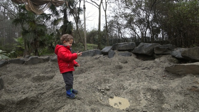 小男孩在泥泞的沙坑里玩耍