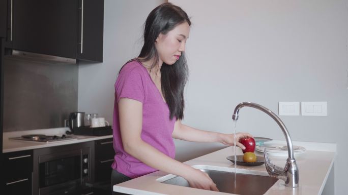 东南亚女子在公寓里洗碗和水果