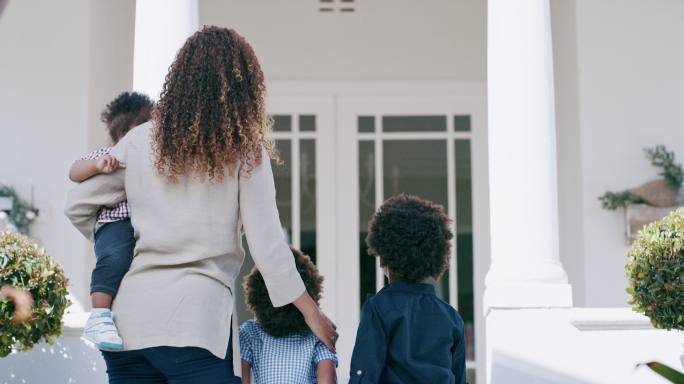 非洲家庭搬进了新家。一位单身母亲买了一栋豪宅后站在前门外的照片。离婚后令人兴奋的新开始
