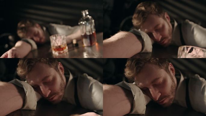 黑暗房间里一位悲伤的醉酒经理在一杯波旁威士忌后的桌子上睡着了