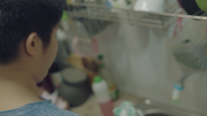 亚洲男孩在家里的厨房里洗碗，男孩帮妈妈做家务。
