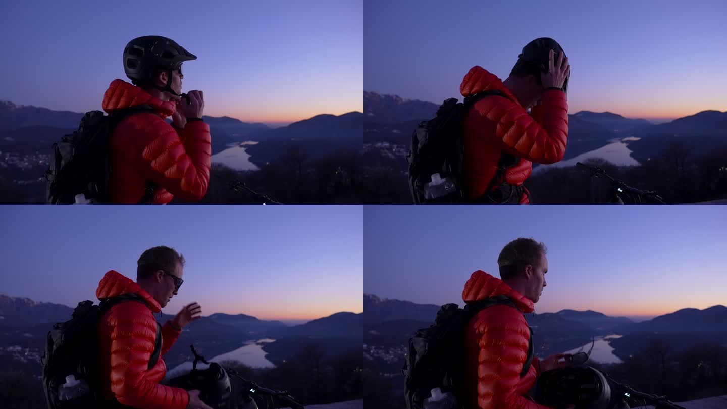 骑山地车的人在日落后的蓝色小时放松身心，欣赏下面的湖泊和山脉