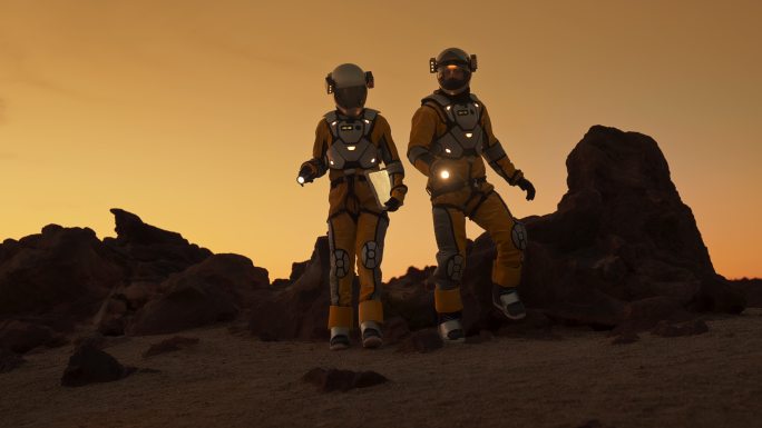 火星上的两名宇航员。在黄昏或黎明时探索外星星球。爬一座岩石山