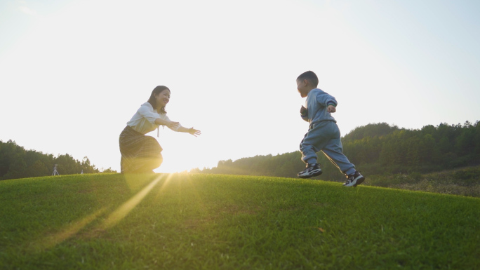 妈妈陪伴小孩草地玩耍温馨逆光拥抱儿童节