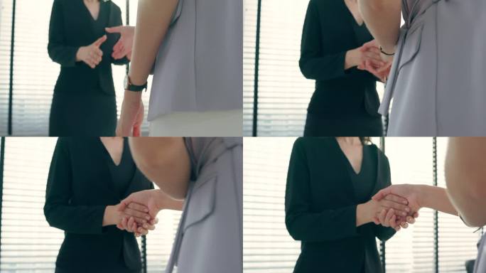 年轻女商人在办公室相互握手的特写镜头。两位有魅力的员工在会议室就商业交易合并进行谈判后，享受合伙协议