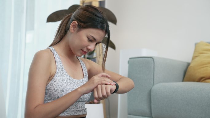 年轻的亚洲女性在锻炼前设置智能手表。