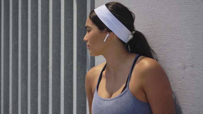 戴着耳机听音乐的年轻女跑步者