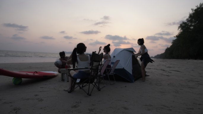 一群亚洲朋友在海滩上露营度假。
