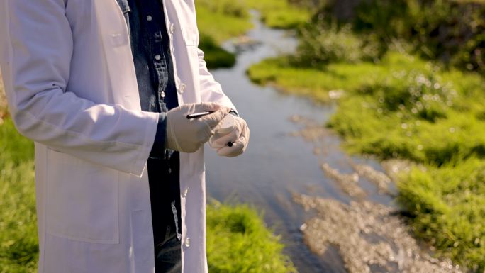 无法识别的男性生态学家和实验室技术人员，从城市河流中取样并在样品瓶上做标记