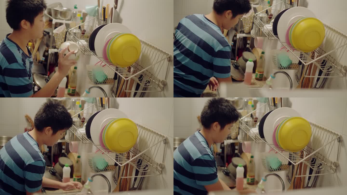 亚洲男孩在家里的厨房里洗碗，男孩帮妈妈做家务。