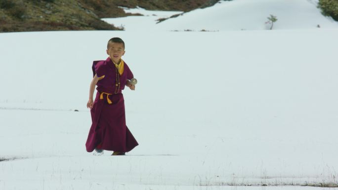 小活佛手持转经筒在雪地行走