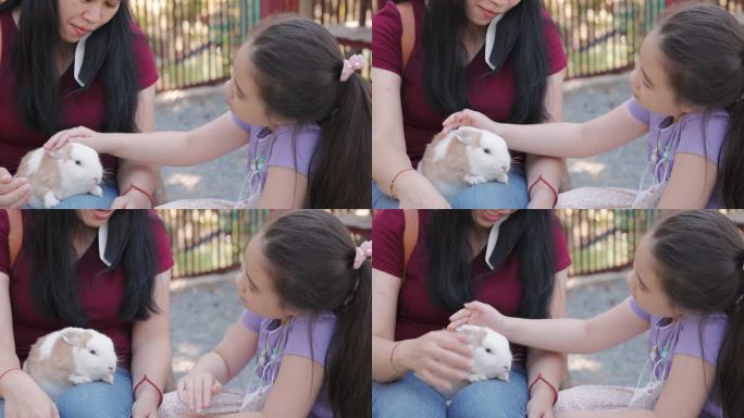 女儿和妈妈抚摸着小兔子