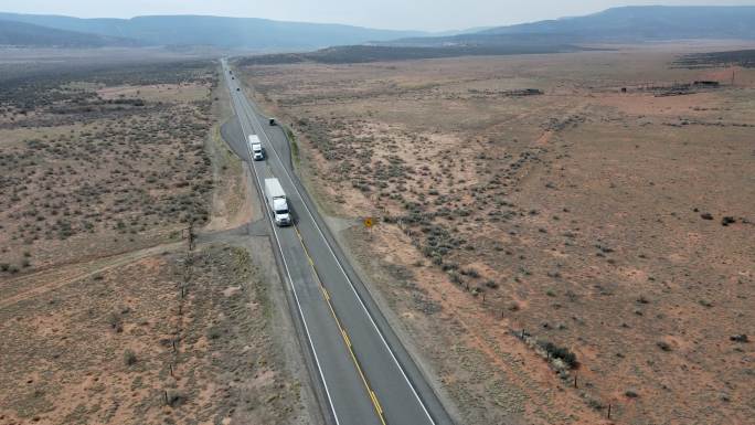 无人机视图半卡车在犹他州西南部靠近摩押的红岩砂岩地区沙漠的四车道公路上加速行驶