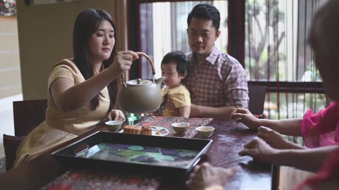 中国女儿在多代人中喝茶，下午茶时在家里享用传统中秋月饼和中国茶