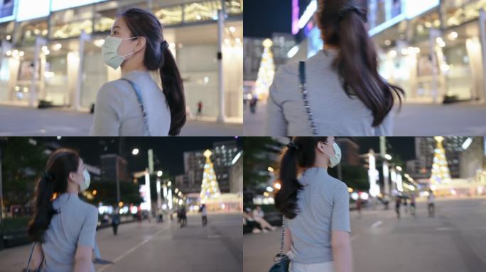 亚洲z世代商业女性微笑着戴着面罩在泰国曼谷暹罗市中心散步，享受夜生活