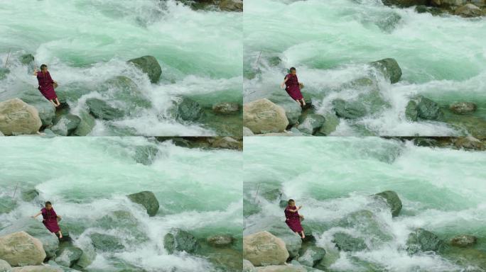 小喇嘛坐在河边石头上打水漂儿