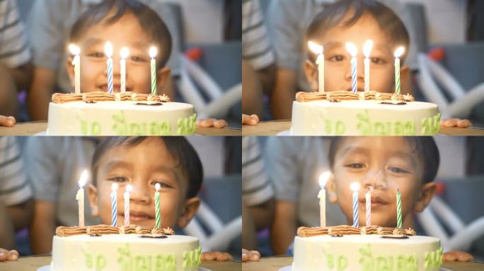 小男孩在聚会上吹灭生日蛋糕上的蜡烛。