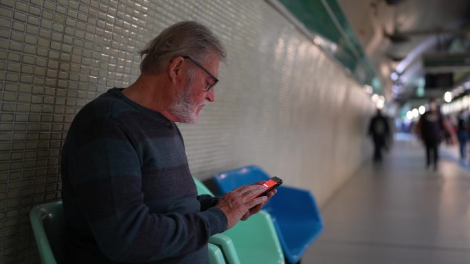 老年人在等地铁列车时使用手机