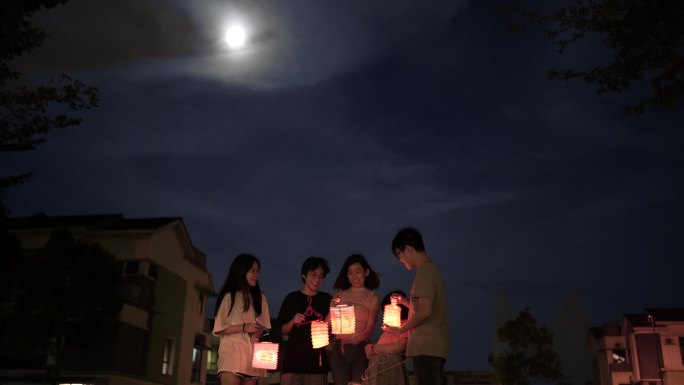 亚裔中国母亲带着孩子和侄子举着纸灯，庆祝中秋节。