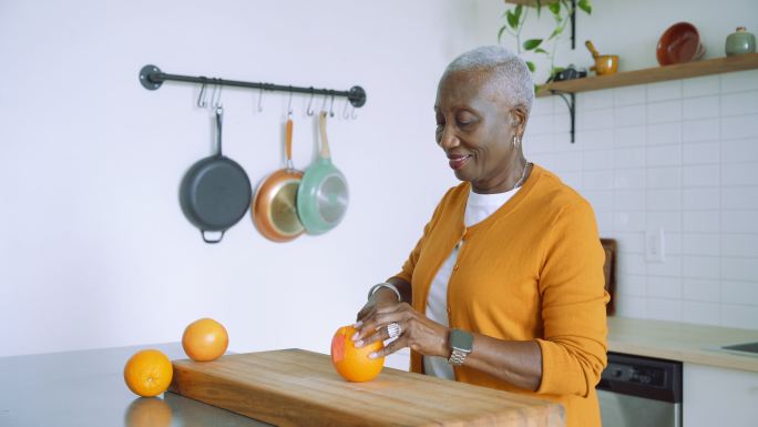 健康的老年妇女切新鲜橙子