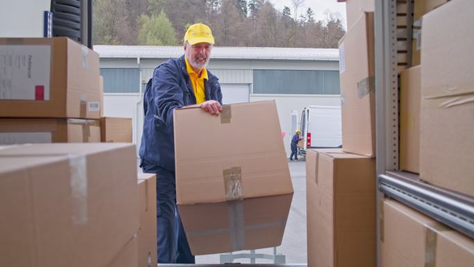 SLO MO高级送货员将包裹装到货车地板上