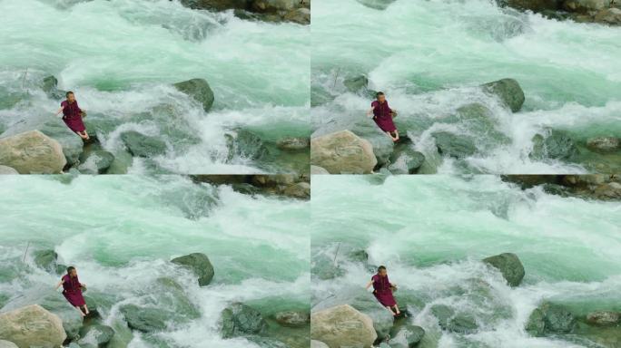 小喇嘛坐在流水旁的石头上