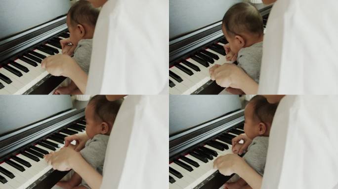 单亲妈妈抱着刚出生的男婴在家里弹钢琴。她教她可爱的孩子演奏古典乐器。