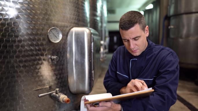 酒厂的工人在酒窖里检查葡萄酒的质量