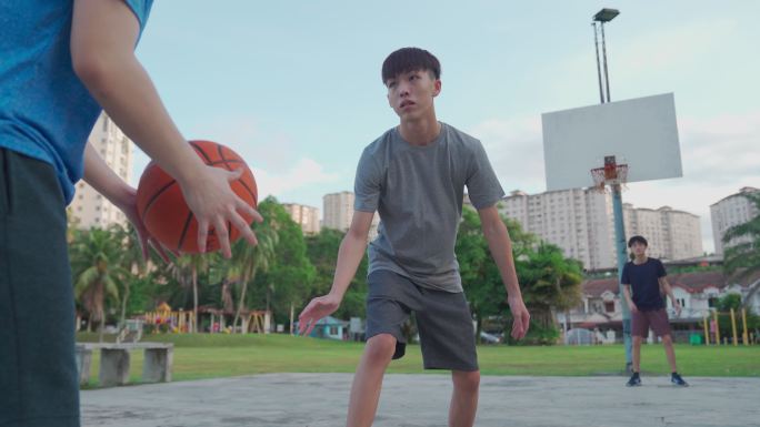 Z世代亚洲华裔少年在周末早上与朋友们一起练习篮球比赛，挑战球员并投篮