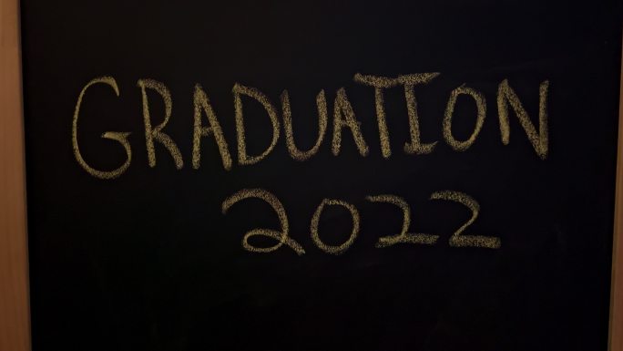 大型黑色黑板，上面用黄色粉笔写着“毕业2022”并下划线