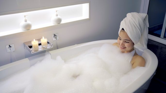 4K镜头特写女人在浴缸里洗澡，玩泡泡。