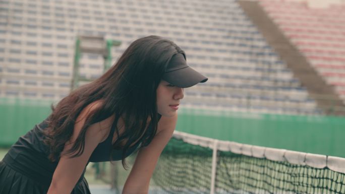 年轻的亚洲女子在网球比赛失利后感到疲惫和失望。