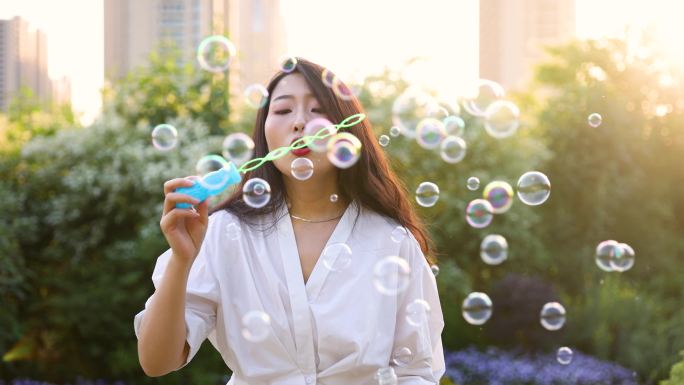 日落时吹肥皂泡的年轻女子