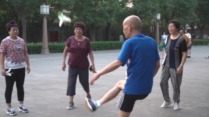 慢动作广场老人健身踢剪子年轻人打羽毛球
