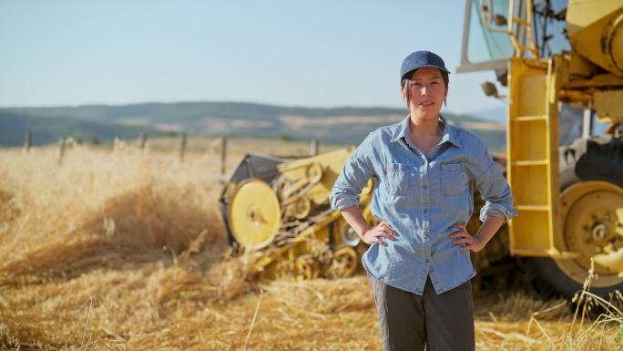年轻女农民在农田里使用联合收割机的肖像