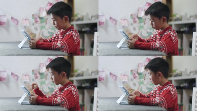 小男孩在餐桌上使用数字平板电脑
