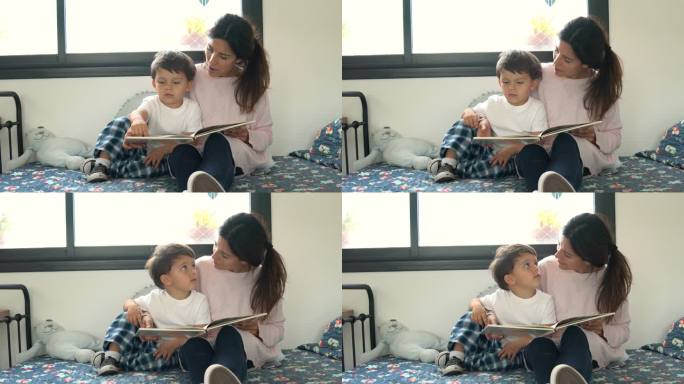 可爱的年轻母亲在睡前给坐在床上玩的儿子读故事