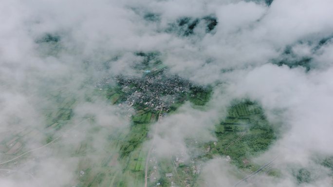 在云层上航拍云南丽江的村庄与田野